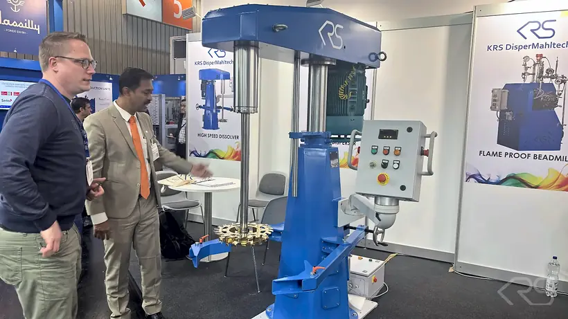 Visitors at the KRS stand at ECS 2025 next to a High Speed Dissolver with control panel